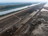 Workers operate large equipment at the construction site of the second phase of the Huaihe River Inlet Waterway project in Qingjiangpu distr...