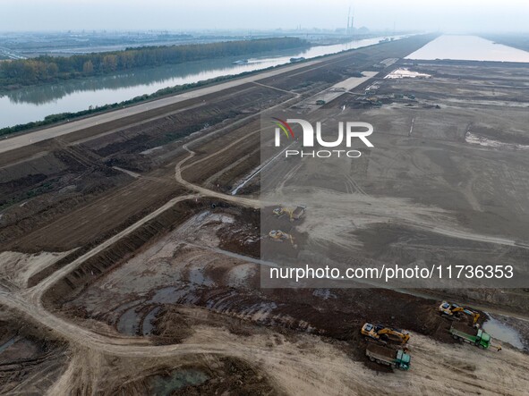 Workers operate large equipment at the construction site of the second phase of the Huaihe River Inlet Waterway project in Qingjiangpu distr...