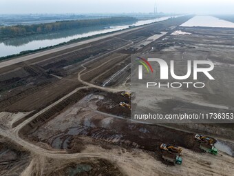 Workers operate large equipment at the construction site of the second phase of the Huaihe River Inlet Waterway project in Qingjiangpu distr...