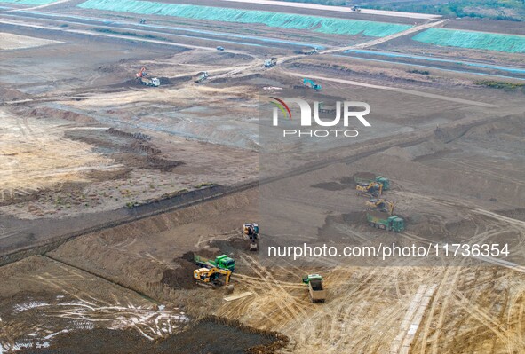 Workers operate large equipment at the construction site of the second phase of the Huaihe River Inlet Waterway project in Qingjiangpu distr...