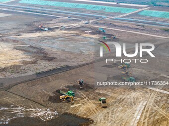 Workers operate large equipment at the construction site of the second phase of the Huaihe River Inlet Waterway project in Qingjiangpu distr...