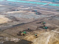 Workers operate large equipment at the construction site of the second phase of the Huaihe River Inlet Waterway project in Qingjiangpu distr...