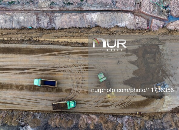 Workers operate large equipment at the construction site of the second phase of the Huaihe River Inlet Waterway project in Qingjiangpu distr...