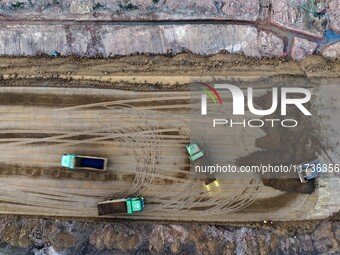 Workers operate large equipment at the construction site of the second phase of the Huaihe River Inlet Waterway project in Qingjiangpu distr...