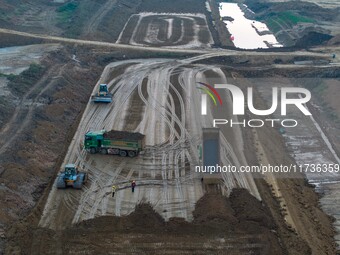 Workers operate large equipment at the construction site of the second phase of the Huaihe River Inlet Waterway project in Qingjiangpu distr...