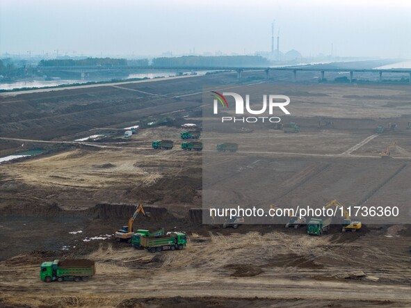 Workers operate large equipment at the construction site of the second phase of the Huaihe River Inlet Waterway project in Qingjiangpu distr...