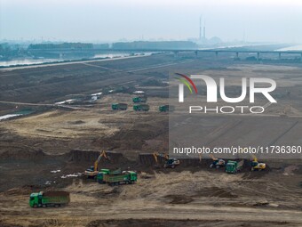 Workers operate large equipment at the construction site of the second phase of the Huaihe River Inlet Waterway project in Qingjiangpu distr...