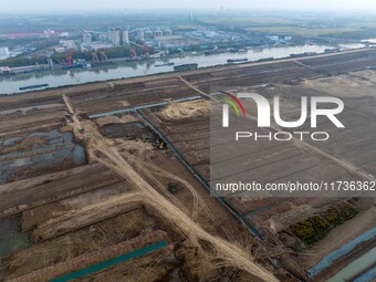 Workers operate large equipment at the construction site of the second phase of the Huaihe River Inlet Waterway project in Qingjiangpu distr...