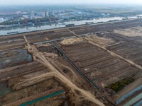 Workers operate large equipment at the construction site of the second phase of the Huaihe River Inlet Waterway project in Qingjiangpu distr...