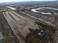 Workers operate large equipment at the construction site of the second phase of the Huaihe River Inlet Waterway project in Qingjiangpu distr...