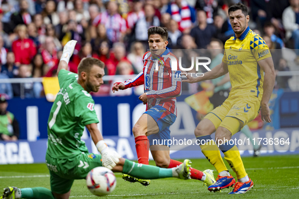 Giuliano Simeone of Atletico de Madrid (C) attempts a kick to score a goal between Jacobus Cillessen of UD Las Palmas (L) and Scott McKenna...