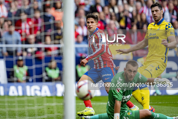 Giuliano Simeone of Atletico de Madrid (L) attempts a kick to score a goal against Jacobus Cillessen of UD Las Palmas (C) and Scott McKenna...