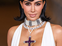 Kim Kardashian wearing a custom Gucci dress and coat with a Tallarico pearl choker, Bvlgari pearl and diamond necklace, and Princess Diana's...