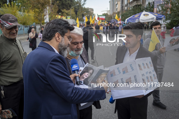 An IRIB News Agency reporter asks a protester about the U.S. 2024 Presidential elections, holding portraits of the election candidates, Dona...