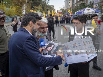 An IRIB News Agency reporter asks a protester about the U.S. 2024 Presidential elections, holding portraits of the election candidates, Dona...