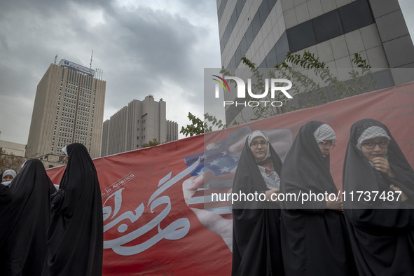 Veiled Iranian schoolgirls stand in front of an anti-U.S. banner after performing in an anti-U.S. and anti-Israel rally marking the annivers...