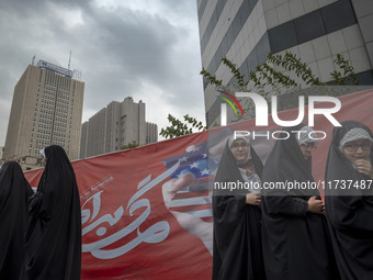 Veiled Iranian schoolgirls stand in front of an anti-U.S. banner after performing in an anti-U.S. and anti-Israel rally marking the annivers...