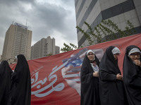 Veiled Iranian schoolgirls stand in front of an anti-U.S. banner after performing in an anti-U.S. and anti-Israel rally marking the annivers...