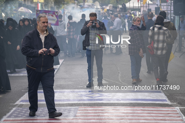 An Iranian photographer takes photographs of the U.S. flag and an Israeli flag during an anti-U.S. and anti-Israel rally marking the anniver...