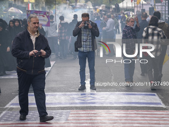 An Iranian photographer takes photographs of the U.S. flag and an Israeli flag during an anti-U.S. and anti-Israel rally marking the anniver...