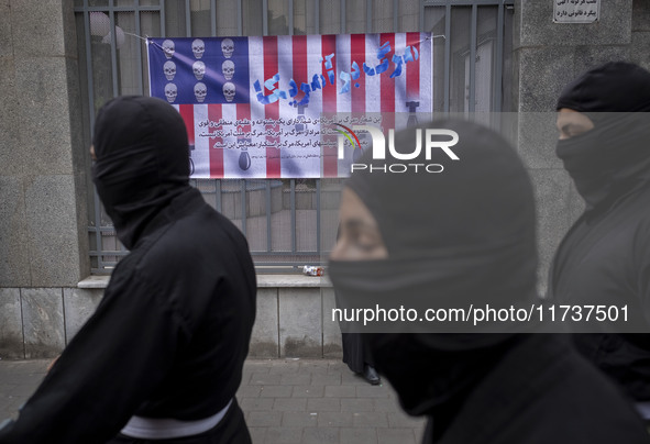 Iranian Ninja men walk past an anti-U.S. banner while participating in an anti-U.S. and anti-Israel rally marking the anniversary of the U.S...