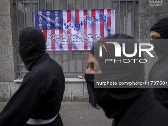 Iranian Ninja men walk past an anti-U.S. banner while participating in an anti-U.S. and anti-Israel rally marking the anniversary of the U.S...