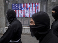 Iranian Ninja men walk past an anti-U.S. banner while participating in an anti-U.S. and anti-Israel rally marking the anniversary of the U.S...