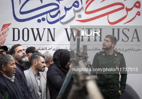 An Islamic Revolutionary Guard Corps (IRGC) military personnel stands in front of an anti-U.S. banner during an anti-U.S. and anti-Israel ra...