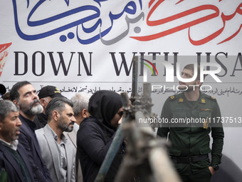 An Islamic Revolutionary Guard Corps (IRGC) military personnel stands in front of an anti-U.S. banner during an anti-U.S. and anti-Israel ra...