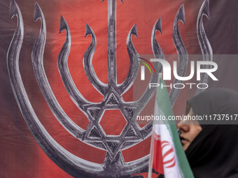 A veiled Iranian woman carries an Iranian flag and walks past an anti-Israeli banner while participating in an anti-U.S. and anti-Israel ral...