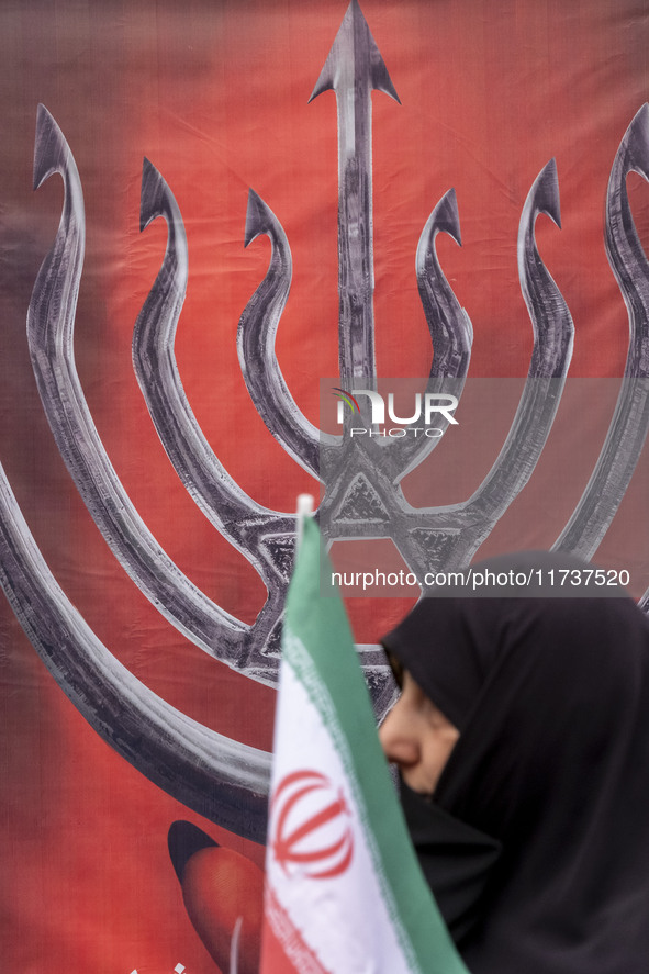 A veiled Iranian woman carries an Iranian flag and walks past an anti-Israeli banner while participating in an anti-U.S. and anti-Israel ral...