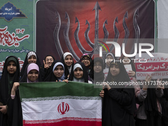 A group of veiled Iranian schoolgirls pose for a photograph while holding an Iranian flag in front of an anti-Israeli banner during an anti-...