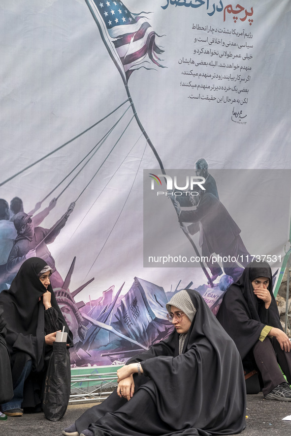 Veiled Iranian women sit in front of an anti-U.S. banner while participating in an anti-U.S. and anti-Israel rally marking the anniversary o...