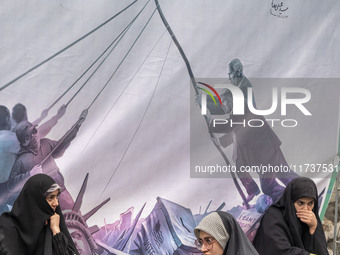 Veiled Iranian women sit in front of an anti-U.S. banner while participating in an anti-U.S. and anti-Israel rally marking the anniversary o...