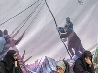 Veiled Iranian women sit in front of an anti-U.S. banner while participating in an anti-U.S. and anti-Israel rally marking the anniversary o...