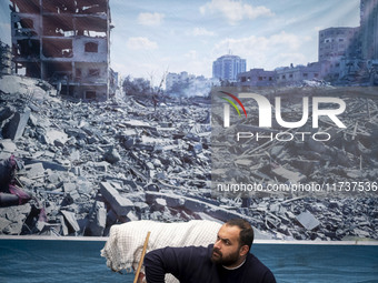 An Iranian man sits under a banner featuring a view of Gaza, which collapses due to Israeli airstrikes, during an anti-U.S. and anti-Israel...