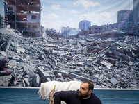 An Iranian man sits under a banner featuring a view of Gaza, which collapses due to Israeli airstrikes, during an anti-U.S. and anti-Israel...