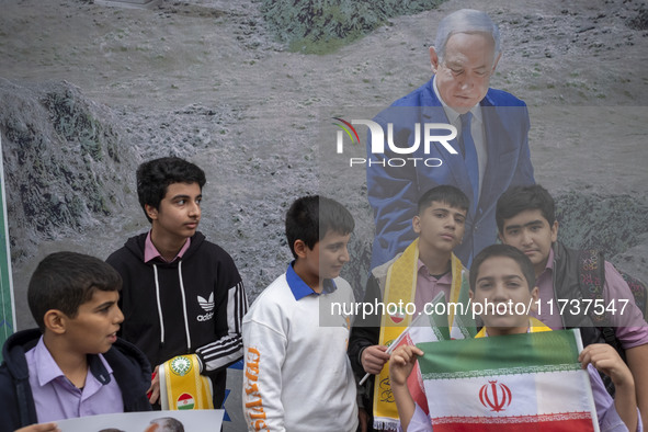 A group of Iranian schoolboys stands in front of a banner featuring a portrait of Israeli Prime Minister Benjamin Netanyahu during an anti-U...