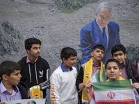 A group of Iranian schoolboys stands in front of a banner featuring a portrait of Israeli Prime Minister Benjamin Netanyahu during an anti-U...