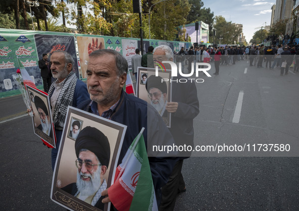 Elderly Iranian men carry portraits of Iran's Supreme Leader, Ayatollah Ali Khamenei, while participating in an anti-U.S. and anti-Israel ra...