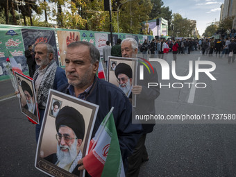 Elderly Iranian men carry portraits of Iran's Supreme Leader, Ayatollah Ali Khamenei, while participating in an anti-U.S. and anti-Israel ra...