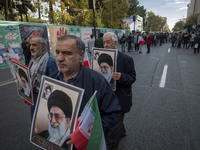 Elderly Iranian men carry portraits of Iran's Supreme Leader, Ayatollah Ali Khamenei, while participating in an anti-U.S. and anti-Israel ra...