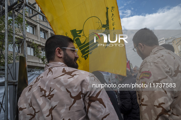 Islamic Revolutionary Guard Corps (IRGC) military personnel stand together under a flag of Lebanon's Hezbollah while taking part in an anti-...