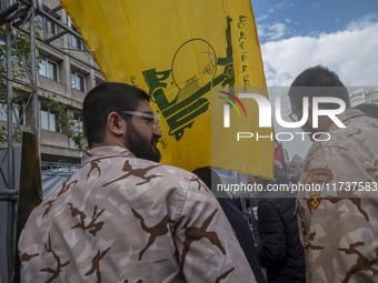 Islamic Revolutionary Guard Corps (IRGC) military personnel stand together under a flag of Lebanon's Hezbollah while taking part in an anti-...