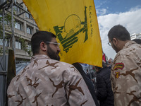 Islamic Revolutionary Guard Corps (IRGC) military personnel stand together under a flag of Lebanon's Hezbollah while taking part in an anti-...