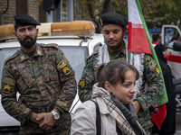 A young Iranian woman who does not wear a mandatory headscarf walks past two military personnel of the Iranian police special forces during...