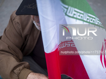 An elderly man holds an Iranian flag during an anti-U.S. and anti-Israel rally marking the anniversary of the U.S. embassy occupation outsid...