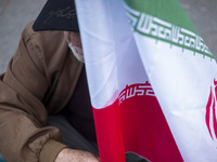 An elderly man holds an Iranian flag during an anti-U.S. and anti-Israel rally marking the anniversary of the U.S. embassy occupation outsid...