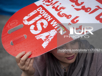 An Iranian woman holds an anti-U.S. placard while participating in an anti-U.S. and anti-Israel rally marking the anniversary of the U.S. em...