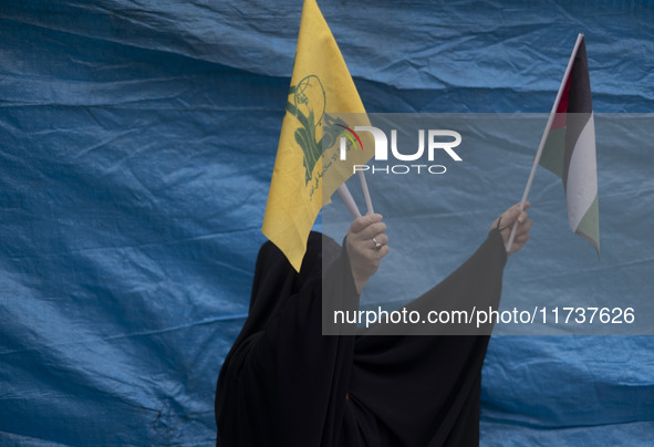 A veiled Iranian woman waves a Palestinian flag and a flag of Lebanon's Hezbollah while participating in an anti-U.S. and anti-Israel rally...